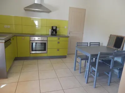 a kitchen with yellow cabinets and a table and chairs at La Maison Bougnette in Flassan