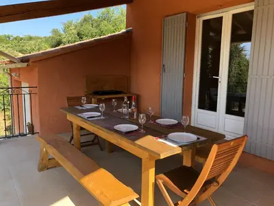 a wooden table and chairs on a patio at La Maison Bougnette in Flassan
