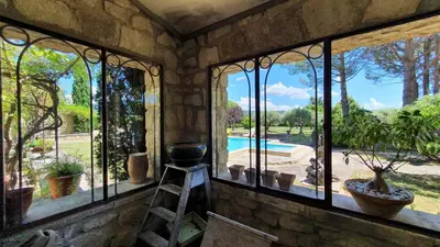 a room with windows looking out at a pool at gîte Mas Antinea in Mazan