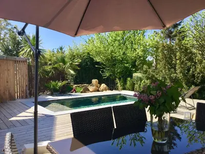 a swimming pool with an umbrella and a vase of flowers at Villa en campagne avec piscine et jacuzzi in Aix-en-Provence