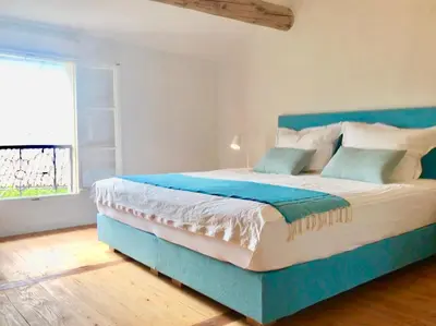 a blue bed in a room with a large window at la bonbonniere - Townhouse Saint-Saturnin-lès-Apt in Saint-Saturnin-les-Apt