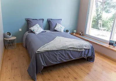 a bedroom with a bed with blue walls and a window at Au Coeur des Vignes en Provence in Châteauneuf-de-Gadagne