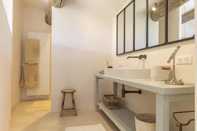 a white bathroom with a sink and a stool at Maison Ventoux in Crillon-le-Brave