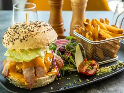 a sandwich and french fries on a black plate at Mercure Aix-en-Provence La Duranne Gare TGV in Aix-en-Provence