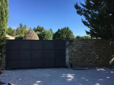 a black garage door with a brick wall at Le Mas les Pléiades - Private pool - Gordes in Gordes