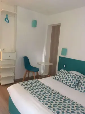 a bedroom with a bed and a blue chair at Brit Hotel Salon de Provence in Salon-de-Provence