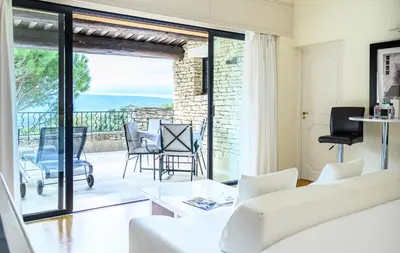 a living room with a white couch and a balcony at Hotel Les Bories & Spa in Gordes