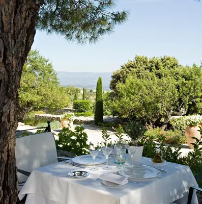 a table with plates and wine glasses on it at Hotel Les Bories & Spa in Gordes