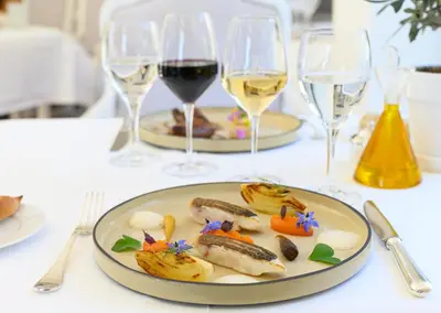 a table with two plates of food and glasses of wine at Hotel Les Bories & Spa in Gordes