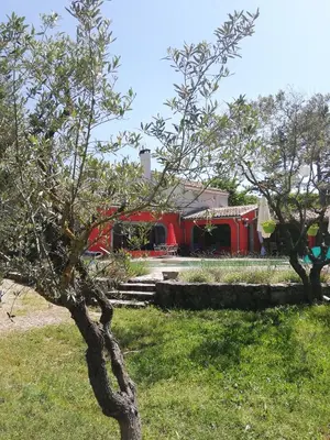 a tree in front of a red building at Le mas de la diligence in Mirabeau