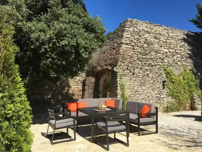 a patio with a table and chairs in front of a building at Le Clos de Manon in Gordes