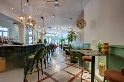 a restaurant with green chairs and a bar at Urban Style Hotel Blason du Ventoux in Carpentras