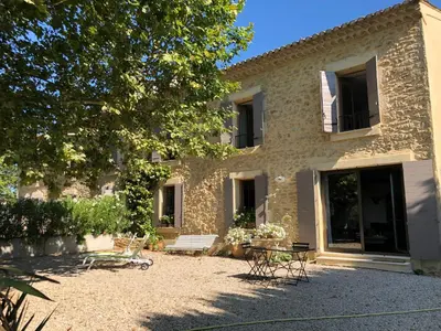 a stone house with a table and chairs in front of it at Le Provençal Duplex piscine jardin le Luberon in Puyvert