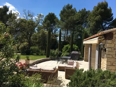 a patio with chairs and a table in a garden at le jas de Saint Hilaire in Ménerbes