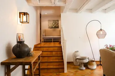 a room with a stairway with a chair and a table at le jas de Saint Hilaire in Ménerbes