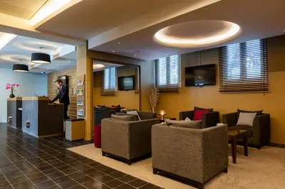 a man standing at a counter in a lobby at Escale Oceania Aix-en-Provence in Aix-en-Provence