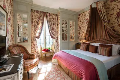 a bedroom with a bed and a chair and windows at Villa Gallici Hôtel & Spa in Aix-en-Provence