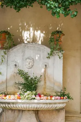 a large stone fountain with flowers in front of a wall at Villa Gallici Hôtel & Spa in Aix-en-Provence