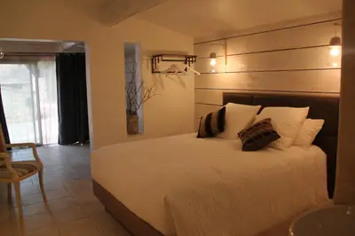 a bedroom with a white bed with a wooden headboard at Le Hameau Fleur de Pierres , Chambre , Gite et Table d'Hôtes in Murs