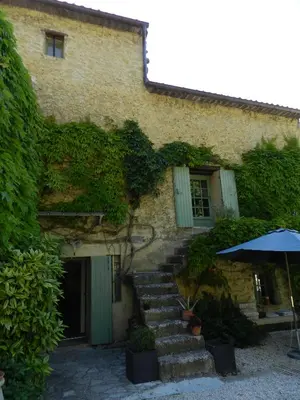 a stone building with stairs and an umbrella at Les Acanthes in Lauris