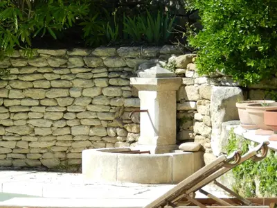 a stone fountain in front of a stone wall at Les Acanthes in Lauris