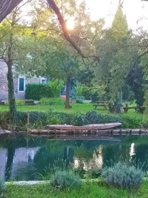 a pond with benches in the middle of a park at Mas Le Pont des Aubes in LʼIsle-sur-la-Sorgue