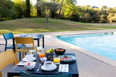 a table with food on it next to a swimming pool at Mas De La Senancole & Spa in Gordes