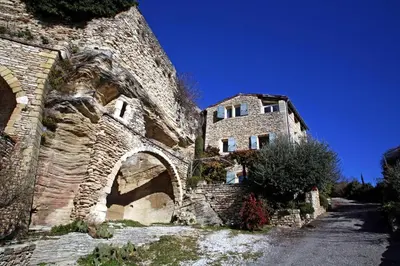 an old stone building with an archway next to a road at Le Bonheur in Gordes