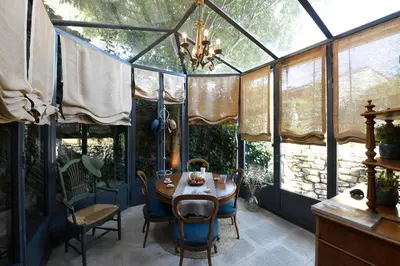 a dining room with a glass house with a table and chairs at Le Bonheur in Gordes