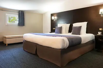 a hotel room with a large bed and a couch at SOWELL HOTELS Domaine de la Petite Isle in LʼIsle-sur-la-Sorgue