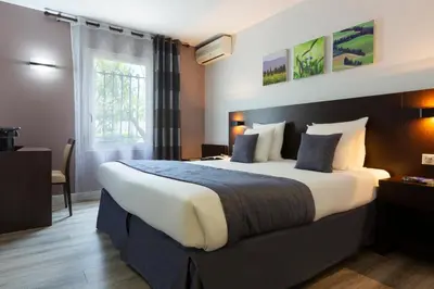 a hotel room with a large bed and a window at SOWELL HOTELS Domaine de la Petite Isle in LʼIsle-sur-la-Sorgue
