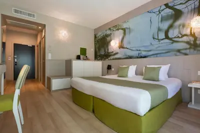 a bedroom with a large bed with a painting on the wall at SOWELL HOTELS Domaine de la Petite Isle in LʼIsle-sur-la-Sorgue