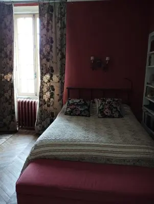 a bedroom with a large bed with red walls at Fenêtre sur vue in Saignon