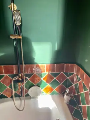 a bathroom with a sink with a shower and a tile wall at Fenêtre sur vue in Saignon