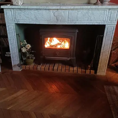 a fireplace with a fire in it in a living room at Fenêtre sur vue in Saignon