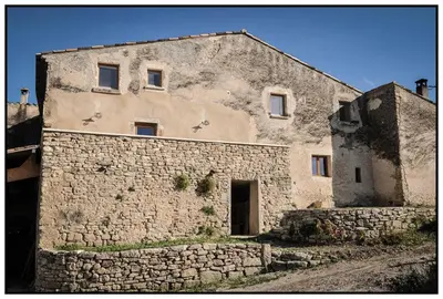 an old stone building with a stone wall at Gîte du Mas Saint-Victor in Bonnieux