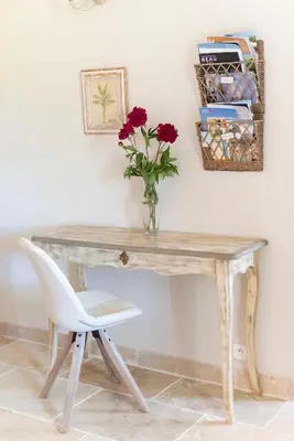 a table with a vase of flowers and a chair at Le Mas Silvestre in Saint-Saturnin-les-Apt