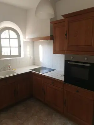 a kitchen with wooden cabinets and a sink and a window at Aux portes du Luberon in Cheval-Blanc