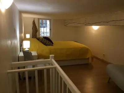 a bedroom with a yellow bed and a staircase at Le calme et la tranquilité à 15 minutes d'Avignon in Caumont-sur-Durance