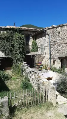 a stone house with a wooden fence in front of it at Sous le Château in Rustrel