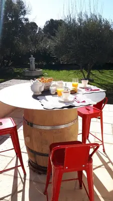 a table and two red chairs next to a wine barrel at l 'oliveraie in Gordes