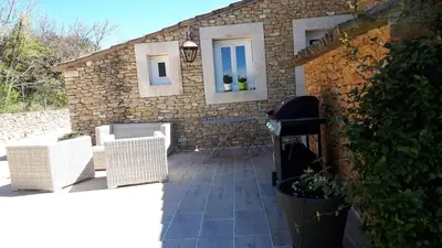a patio with two wicker chairs and a stone building at l 'oliveraie in Gordes
