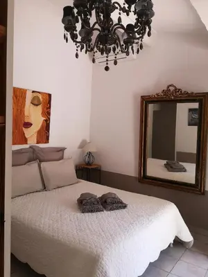 a bedroom with a bed with a mirror and a chandelier at Domaine en Provence Gîte la Ferrandiere in Carpentras