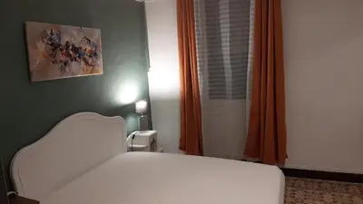 a bedroom with a white bed and an orange curtain at le Mas d'Hubert in LʼIsle-sur-la-Sorgue