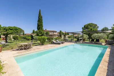 a swimming pool in a yard with a table and chairs at Mas OREA in Gordes