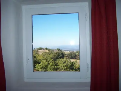 a window in a room with a red curtain at La Bastide de Ninou maison de vacances Luberon in Viens