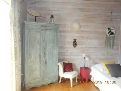 a bedroom with a green cabinet and a chair at La maison bleue in LʼIsle-sur-la-Sorgue