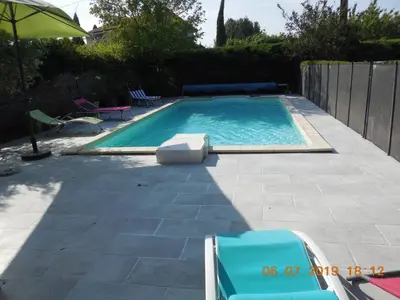 a swimming pool with two chairs and an umbrella at La maison bleue in LʼIsle-sur-la-Sorgue