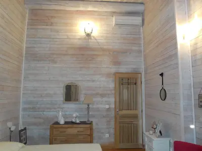 a room with a wooden wall with a bed and a table at La maison bleue in LʼIsle-sur-la-Sorgue