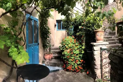 an entrance to a house with a blue door and some flowers at Charmante maison de village à Fontaine-de-Vaucluse in Fontaine-de-Vaucluse